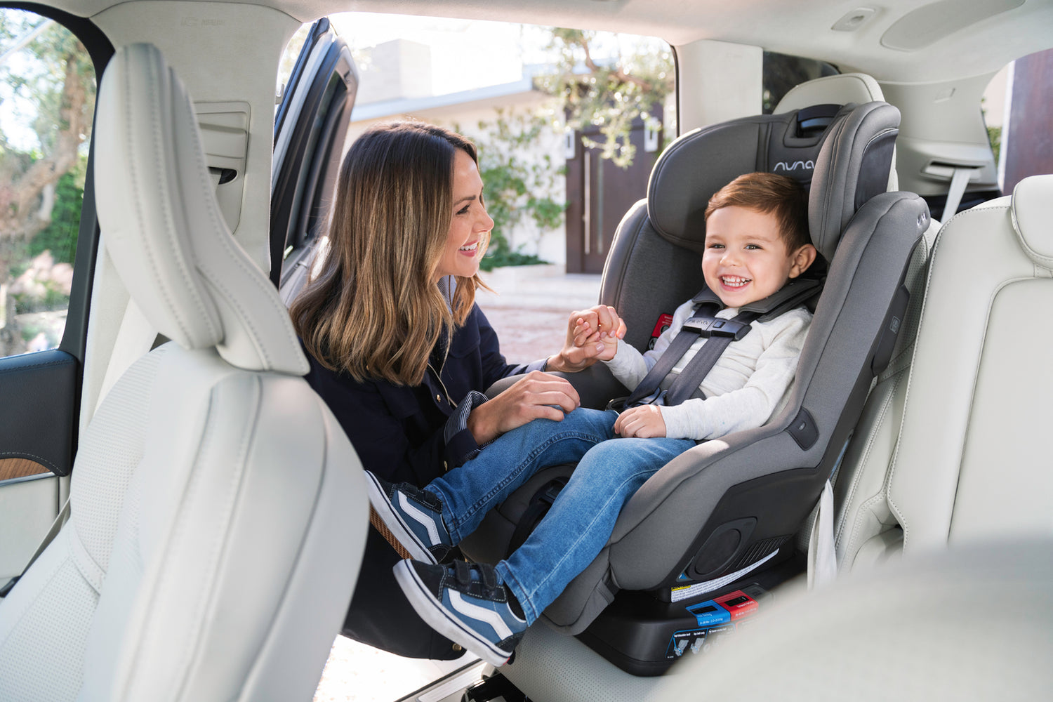 mom strapping her child into a nuna rava convertible car seat in the forward facing position
